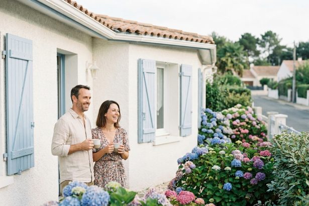 Couple devant une maison individuelle avec jardin à Royan, façade blanche et volets bleus typiques de la région